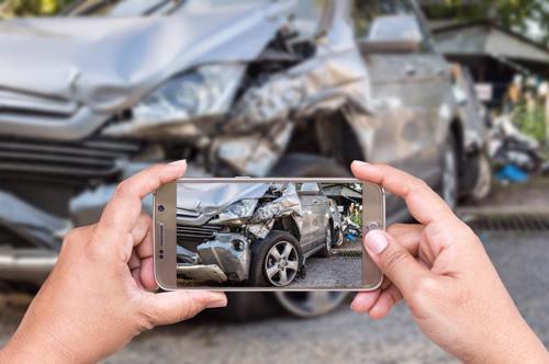 A person taking photos of damage their car received in an accident to send to their insurance provider.