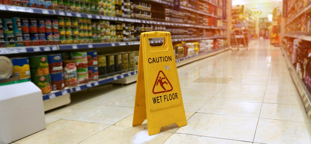 A wet floor sign in the middle of an isle at a grocery store.