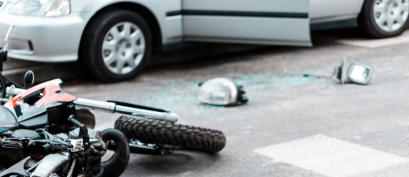 Image of a motorcycle on the ground next to a car after a collision
