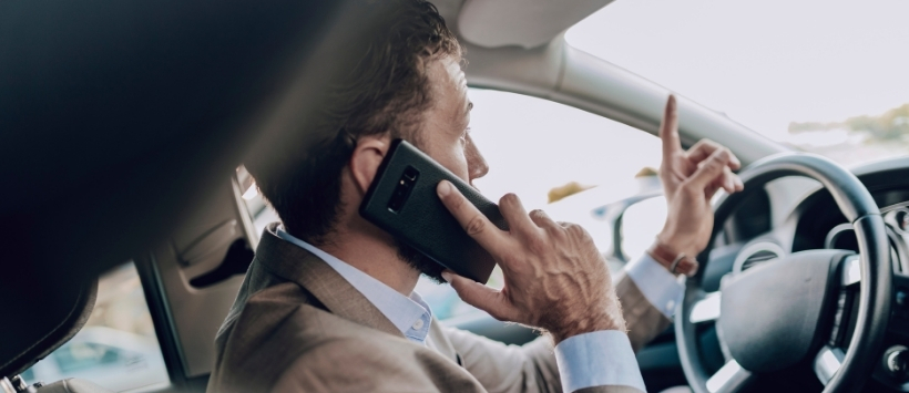 Image of a man talking on the phone while sitting behind the wheel.