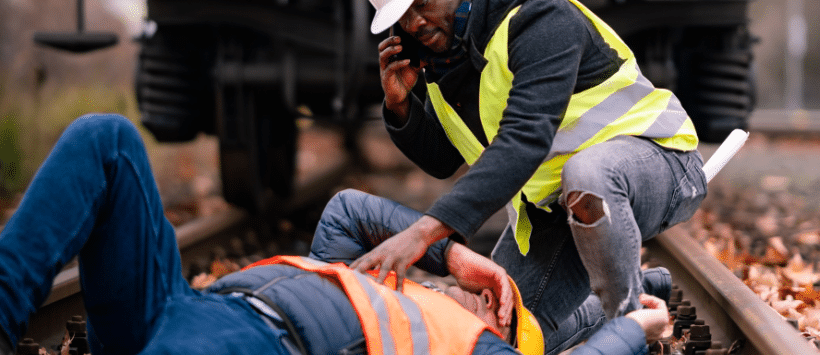 Image of a worker in a fluorescent vest lying on the ground in pain